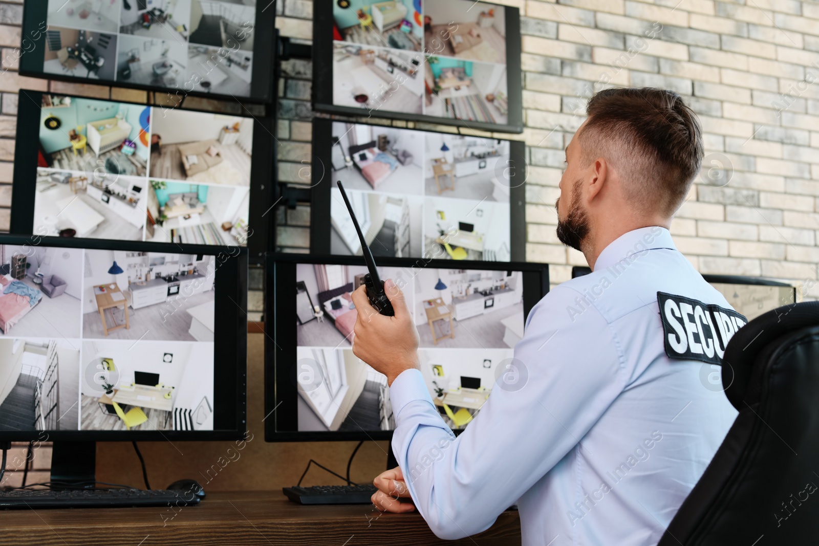 Photo of Male security guard with portable transmitter monitoring modern CCTV cameras indoors