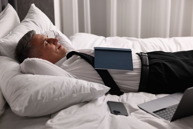 Businessman in office clothes sleeping on bed indoors