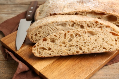 Photo of Tasty freshly baked bread on wooden table, closeup