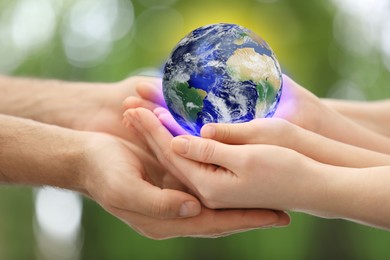 Image of World in our hands. Closeup view of parents and kid holding digital model of Earth on blurred green background, space for text 