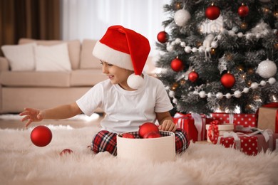 Cute little girl with box of Christmas balls at home