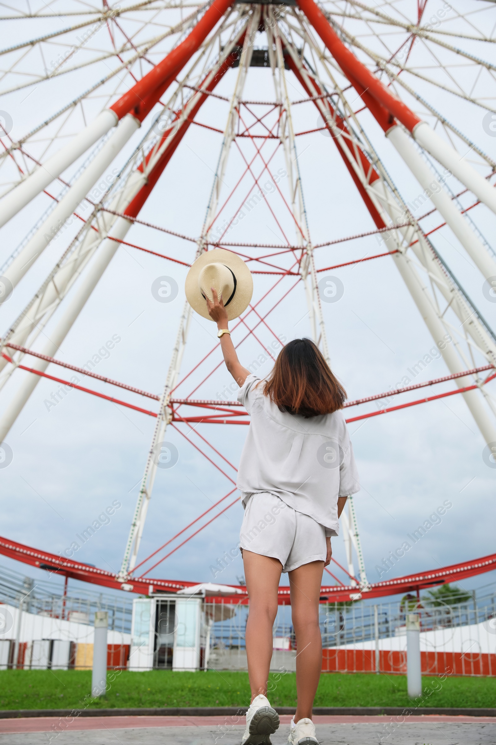 Photo of Young woman near Ferris wheel outdoors, low angle view