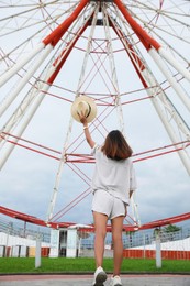 Photo of Young woman near Ferris wheel outdoors, low angle view
