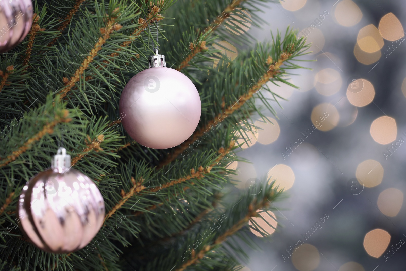 Photo of Shiny lilac balls hanging on Christmas tree against festive lights