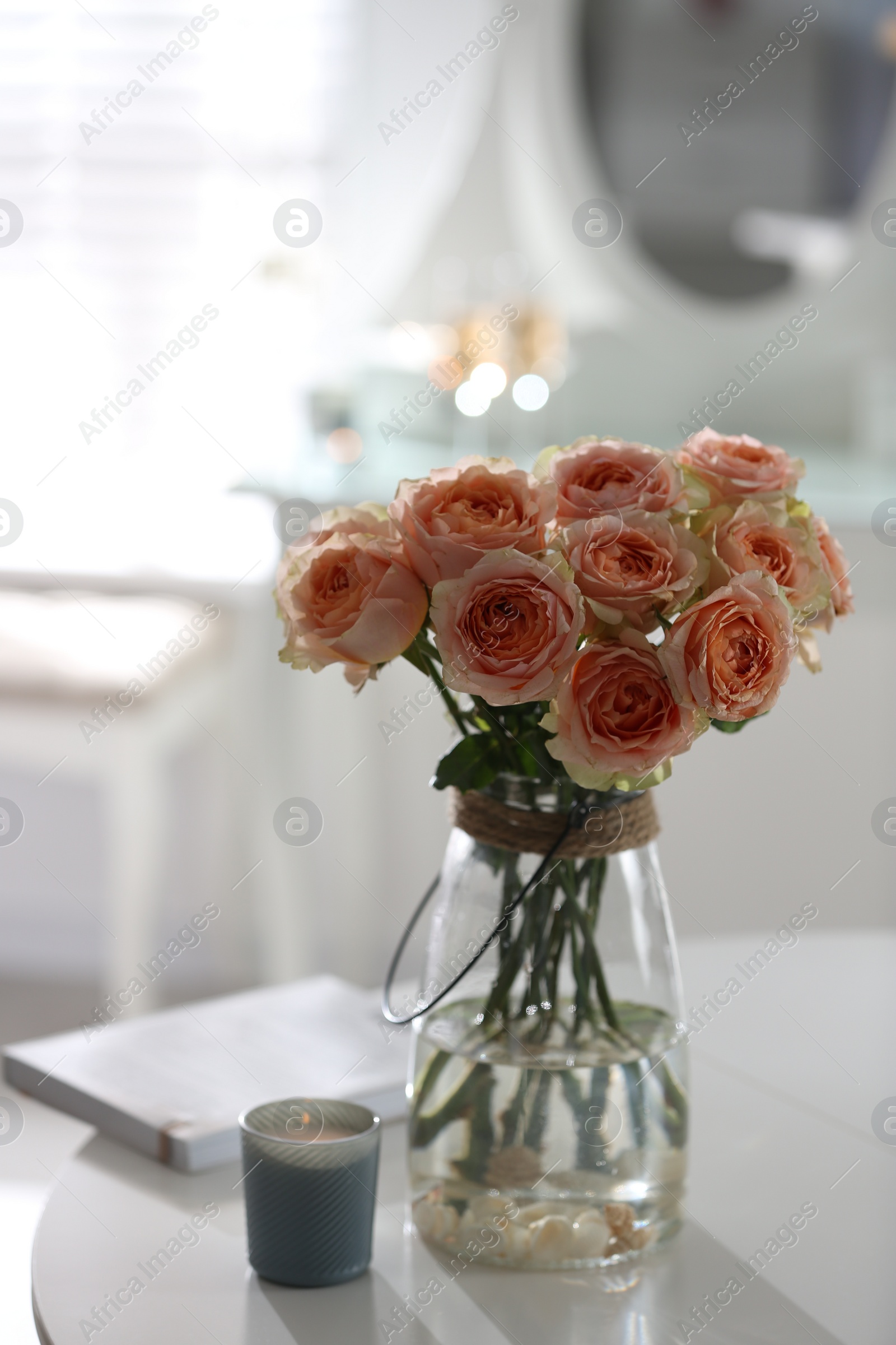 Photo of Glass vase with beautiful flowers on table in modern room interior