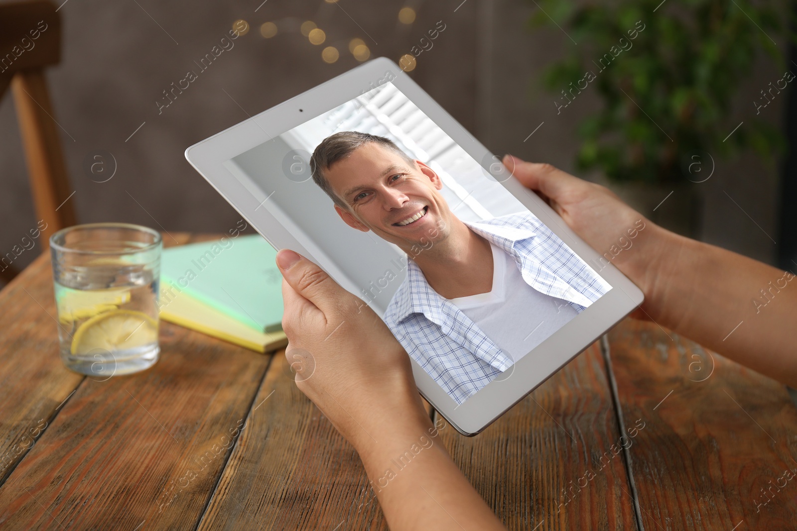 Image of Woman talking with handsome man using video chat on tablet at wooden table, closeup. Online dating