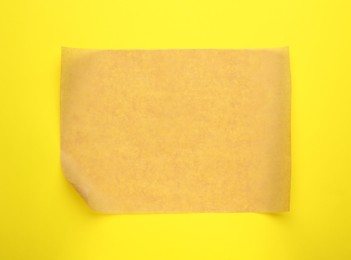 Sheet of brown baking paper on yellow background, top view