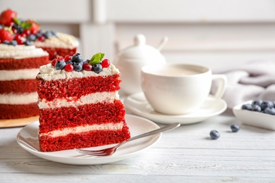 Photo of Plate with piece of delicious homemade red velvet cake on table