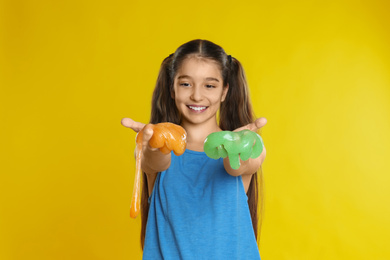 Photo of Preteen girl with slime on yellow background