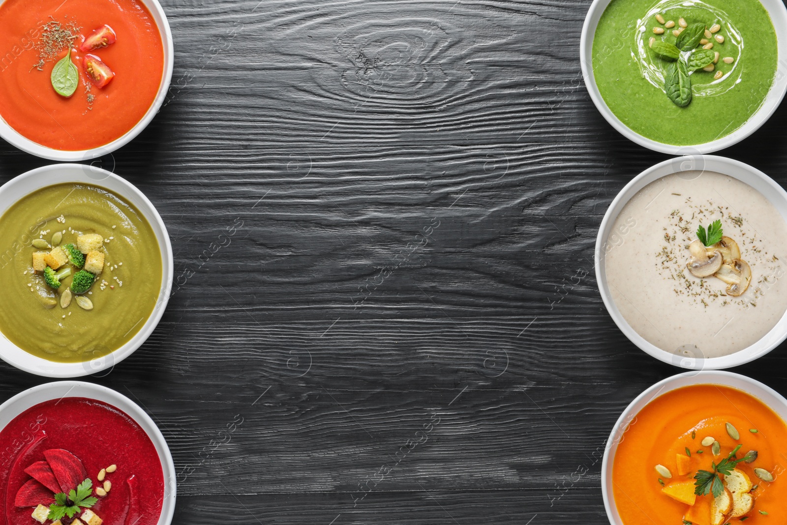 Photo of Various soups in bowls and space for text on wooden background, top view. Healthy food