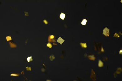 Photo of Shiny golden confetti falling down on black  background