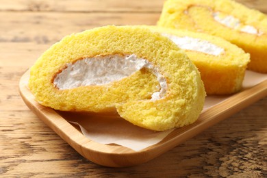 Delicious cake roll with cream filling on wooden table, closeup