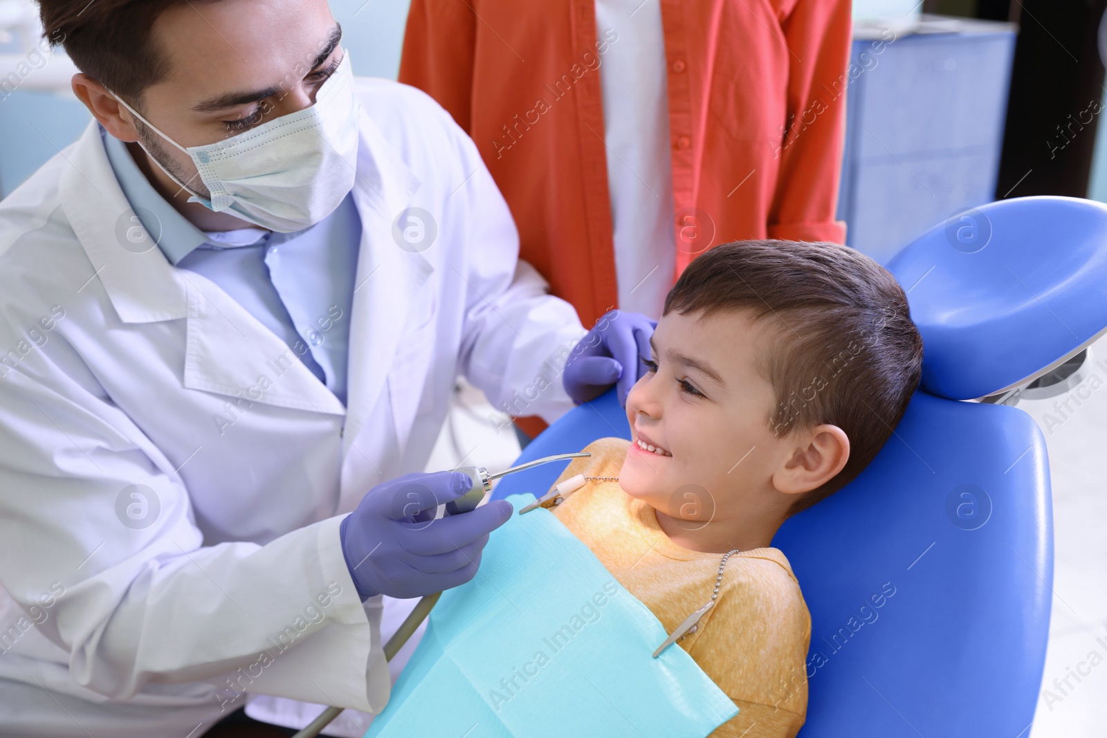 Photo of Professional dentist working with little patient in modern clinic