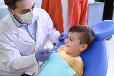 Professional dentist working with little patient in modern clinic