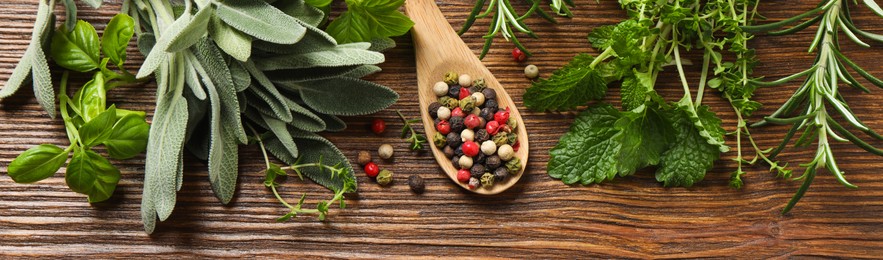 Different fresh herbs and spices on wooden table, flat lay. Banner design