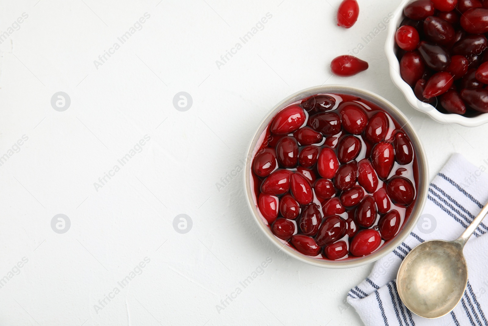 Photo of Delicious dogwood jam with berries on white table, flat lay. Space for text