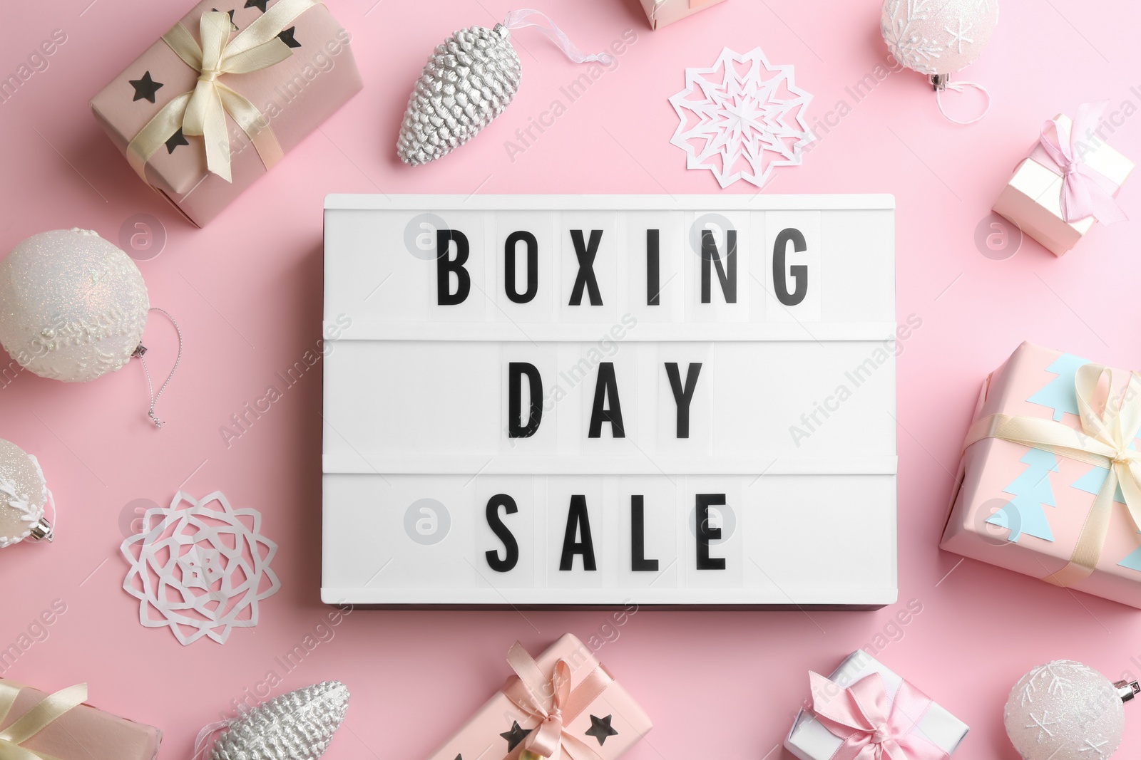 Photo of Lightbox with phrase BOXING DAY SALE and Christmas decorations on light pink background, flat lay