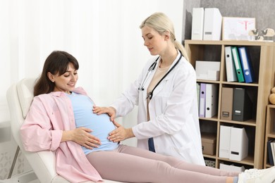 Photo of Pregnancy checkup. Doctor examining patient's tummy in clinic