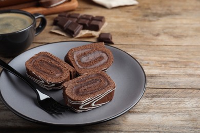 Tasty chocolate cake roll with cream on wooden table, space for text