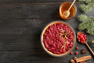 Photo of Flat lay composition with cranberry sauce in plate on wooden background. Space for text