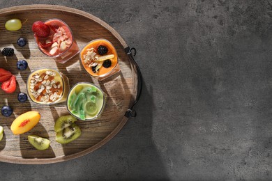 Photo of Tray with many different delicious smoothies and ingredients on grey table, top view. Space for text