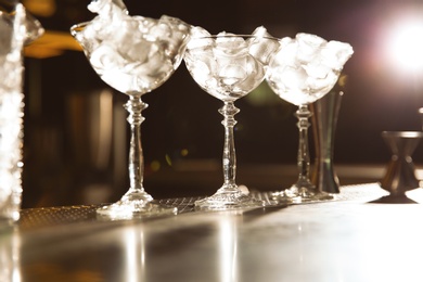 Photo of Martini glasses with ice cubes on bar counter. Space for text
