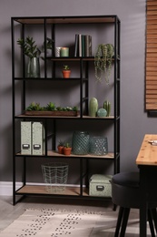 Photo of Shelving with different decor, books and houseplants near gray wall in room. Interior design