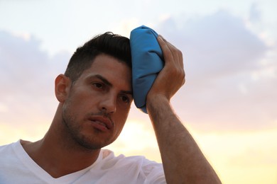Photo of Man with cold pack suffering from heat stroke outdoors at sunset