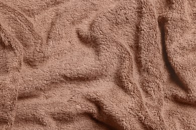 Photo of Soft crumpled brown towel as background, top view