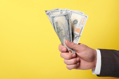 Photo of Man holding money on yellow background, closeup. Space for text. Currency exchange