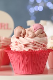 Photo of Beautifully decorated baby shower cupcake for girl with cream on white table, closeup