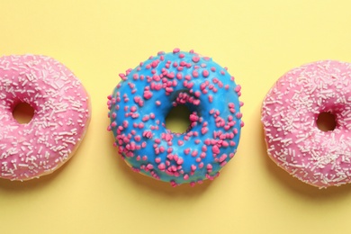 Photo of Delicious glazed doughnuts on color background, top view