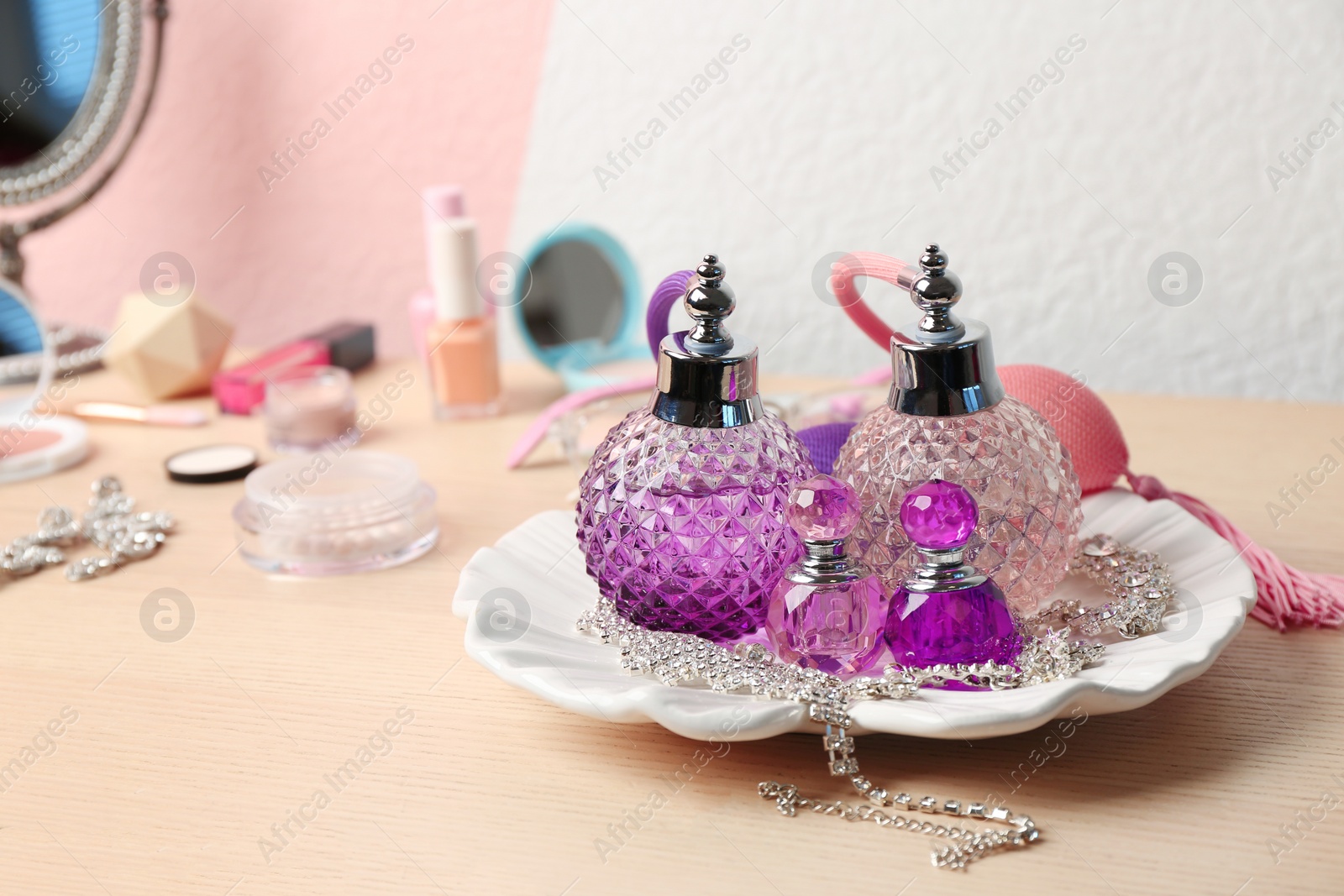 Photo of Plate with perfume bottles and jewellery on dressing table. Space for text