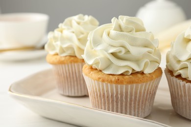 Photo of Tasty cupcakes with vanilla cream on white wooden table, closeup