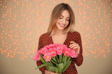 Portrait of smiling young girl with beautiful tulips on blurred background. International Women's Day