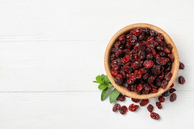 Tasty dried cranberries and leaves on white table, flat lay. Space for text