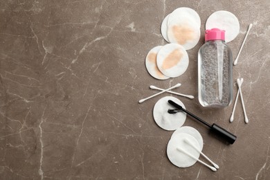 Dirty cotton pads, swabs, mascara and micellar cleansing water on grey background, flat lay. Space for text