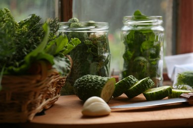 Glass jars, fresh vegetables and herbs on wooden table indoors. Pickling recipe