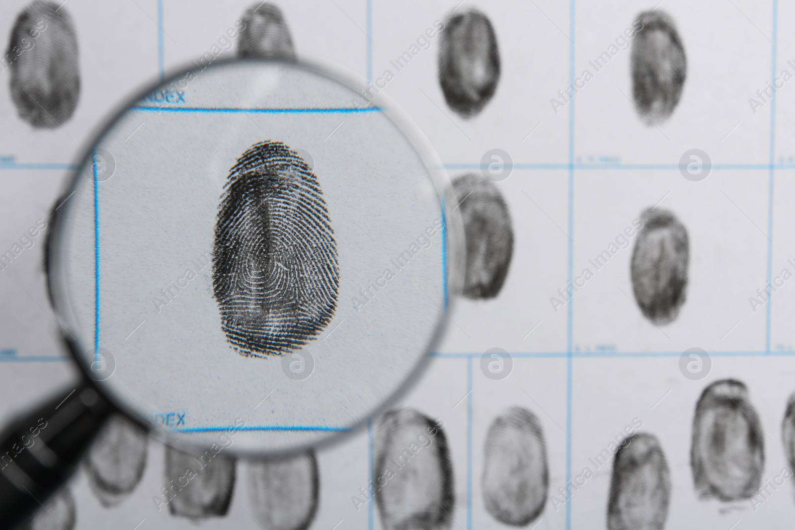 Photo of Magnifying glass and criminal fingerprint card, top view