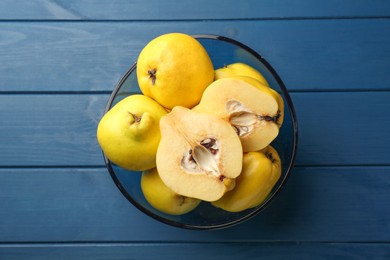 Photo of Tasty ripe quinces in bowl on blue wooden table, top view