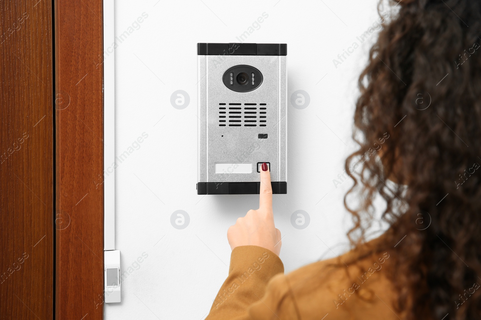 Photo of African-American woman ringing intercom with camera in entryway