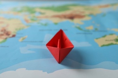 Photo of Red paper boat on world map, closeup