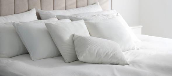 Image of Comfortable bed with soft white pillows indoors. Banner design