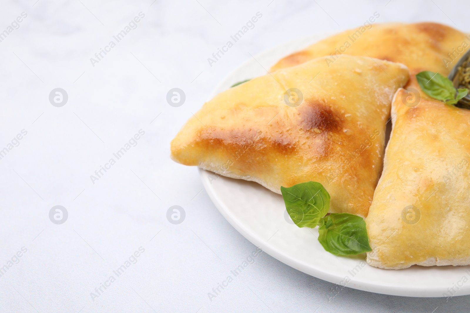 Photo of Delicious samosas and basil on white table, closeup. Space for text