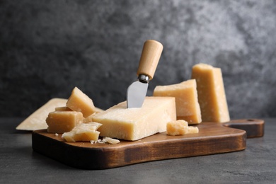 Photo of Parmesan cheese with knife on grey table