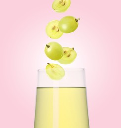 Image of Freshly made grape juice on pink background. Cut and whole berries falling into glass