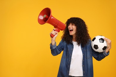 Photo of Happy fan with soccer ball using megaphone on yellow background, space for text