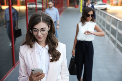 Photo of Young woman with smartphone on city street
