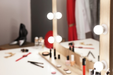 Photo of Blurred view of table with makeup products and mirror in dressing room, closeup