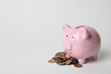 Photo of Cute piggy bank and coins on light background. Space for text